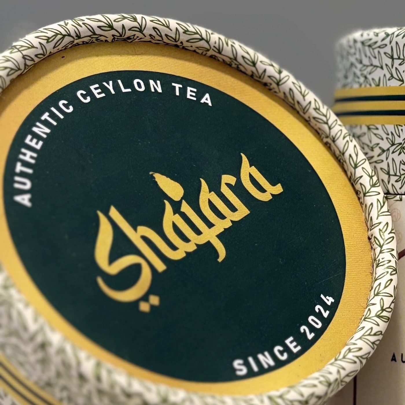 The Shajara wordmark in gold on a green canister lid